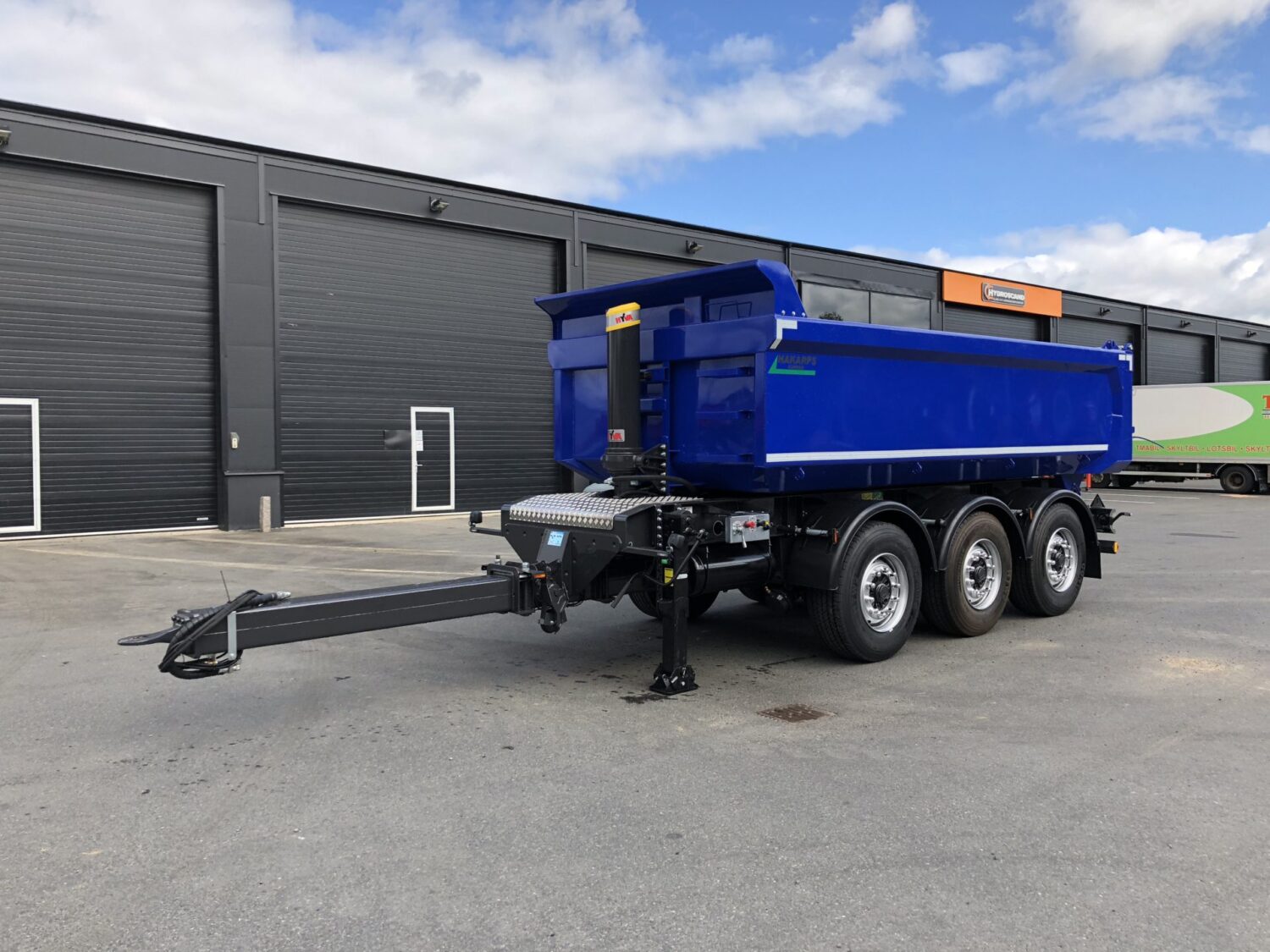 En blå tippkärra framför industribyggnad. En av många tippkärror hos Hakarps.