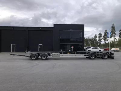 Lastväxlarvagn med rullbanor framför byggnad.