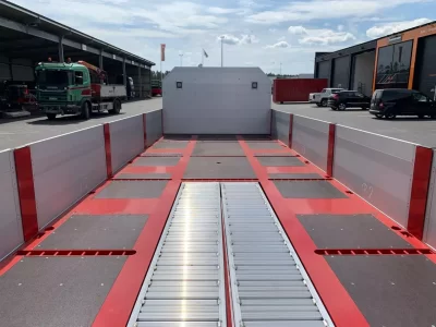 Röd flakvagn framför byggnader.