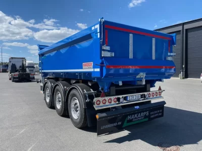 En blå dumperkärra framför en lastbil.