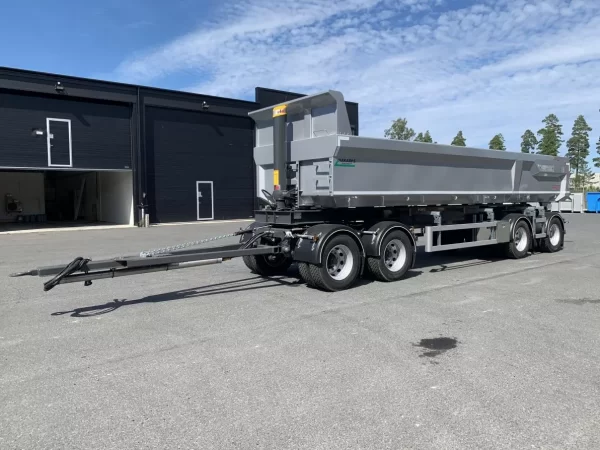 En grå dumper framför halvt öppet garage.