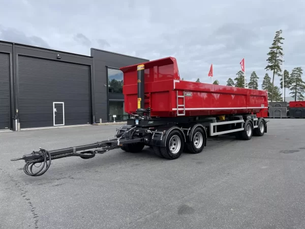 En röd dumper framför byggnad.