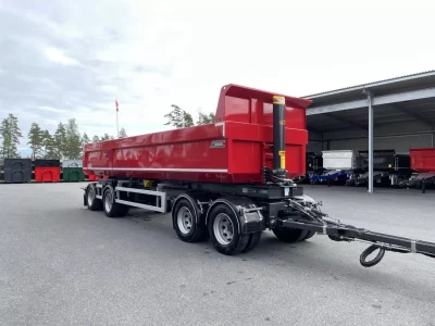 En röd dumper framför carport.