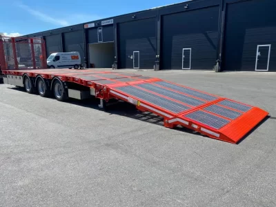 Röd maskintransport med nedfälld ramp.