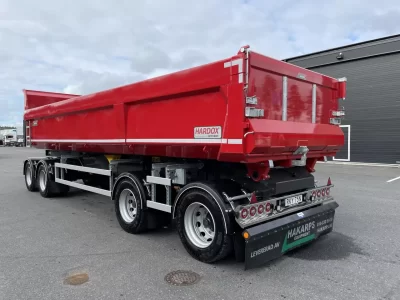 En röd dumper framför ett garage.