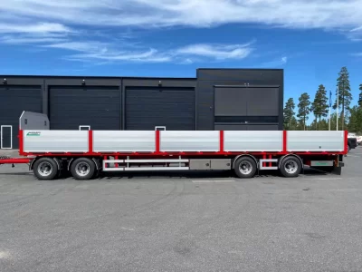 Lång röd flakvagn från sidan.