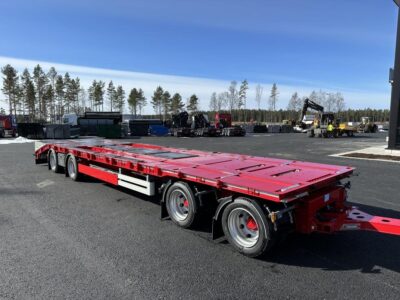 Röd kombivagn snett framifrån med fordon i bakgrunden.