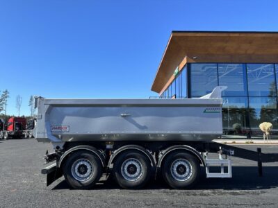 Dumperkärra med kort dragstång från sidan med Hakarps i bakgrunden.