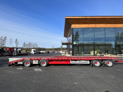 Kombivagn i färgen röd med byggnad.