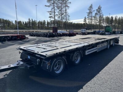 En kombivagn uppställd snett framför trädlinje.