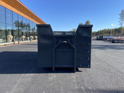 Svart container framför hus.