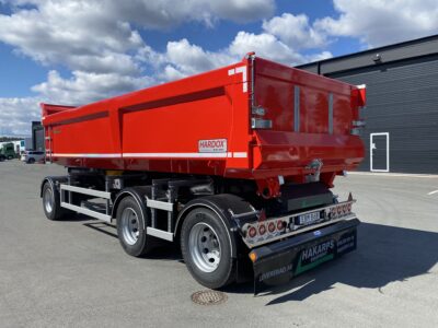 En röd dumpervagn med ett garage i bakgrunden.