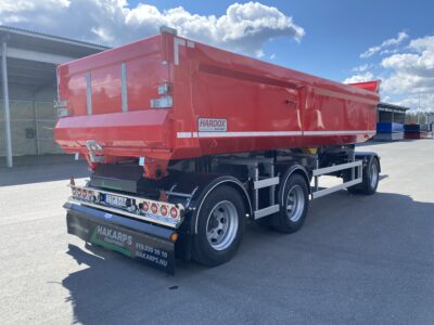 En röd dumpervagn med blå himmel och moln i bakgrunden.