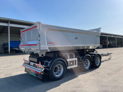 Grå dumperkärra framför öppet garage.