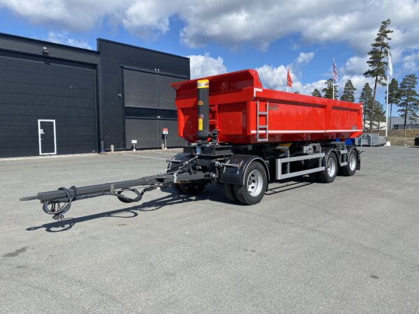 En röd dumpervagn framför en garageport.