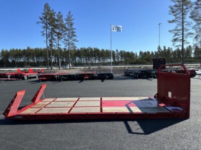 Maskinflak med stegar i flaket framför stor väg.