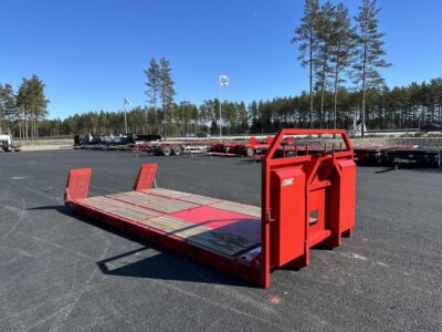 Maskinflak med stegar i flaket framför väg och flaggor.