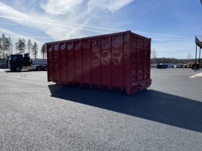 Röd snöcontainer med lastbil bakom.