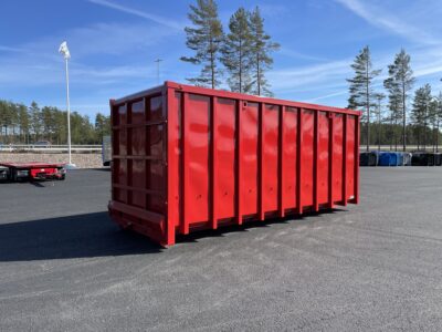 Röd snöcontainer med träd och flagga bakom.