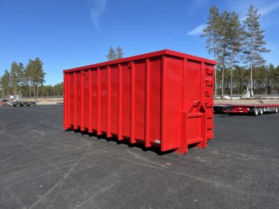 Röd snöcontainer med träd bakom.