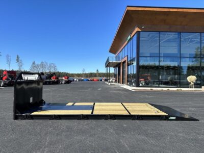 Maskinflak med fast ramp framför Hakarps och fordon.