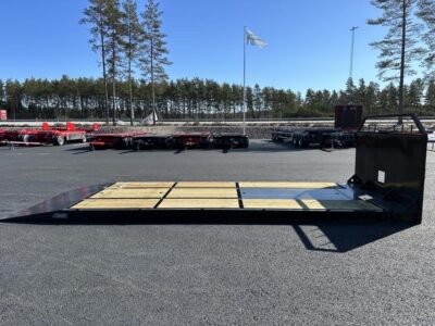 Maskinflak med fast ramp från sidan framför vajande flagga.