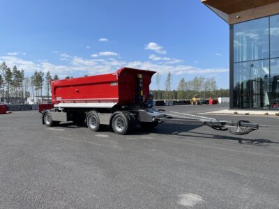 Röd 30 ton dumperkärra med gul traktor i bakgrunden.