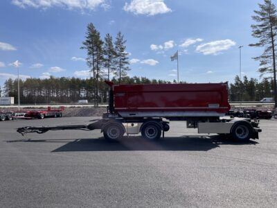 röd 30 ton dumperkärra från sidan med väg och flaggor bakom.