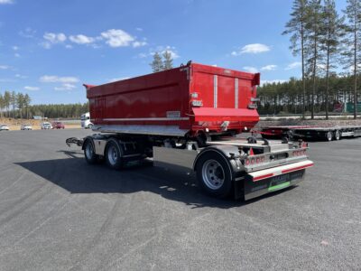 Röd 30 ton dumperkärra med tallar bakom.