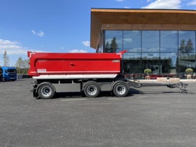 röd 30 ton dumperkärra framför en större byggnad