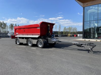 Röd 30 ton dumperkärra framkör byggnad