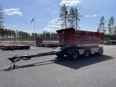 Röd 30 ton dumperkärra framför träd och en väg.