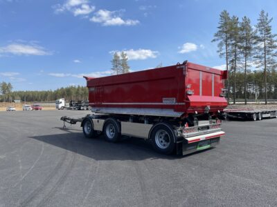 röd 30 ton dumperkärra från sidan med träd och moln i bakgrunden.